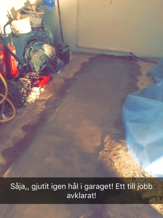 Nyutgjuten betong som täpper till ett hål i ett garage, med verktyg och byggmaterial runtomkring.