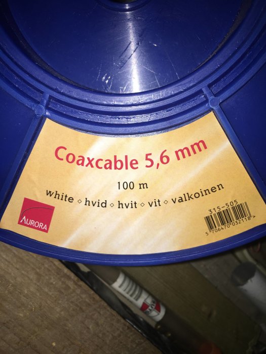 Rulle med vit coaxialkabel märkt "Coaxcable 5,6 mm" och längden 100 m på blå spole med Aurora-logotyp.