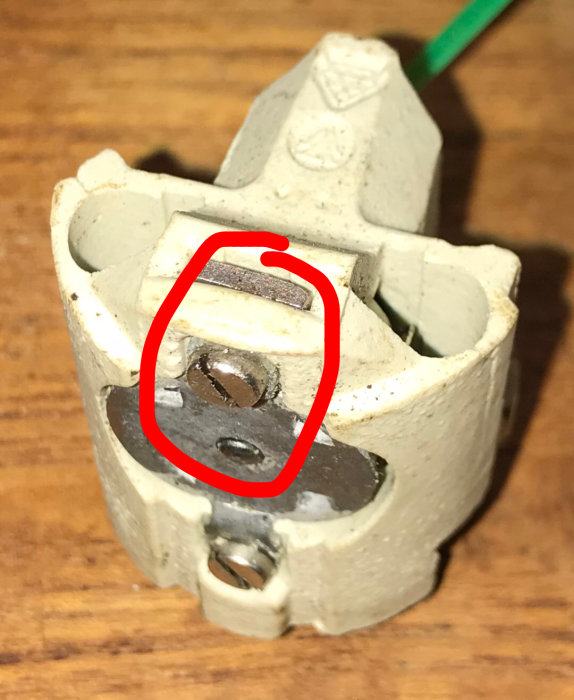 Isärskruvad lampsockel med en potentiell jordningsskruv inringad i rött.
