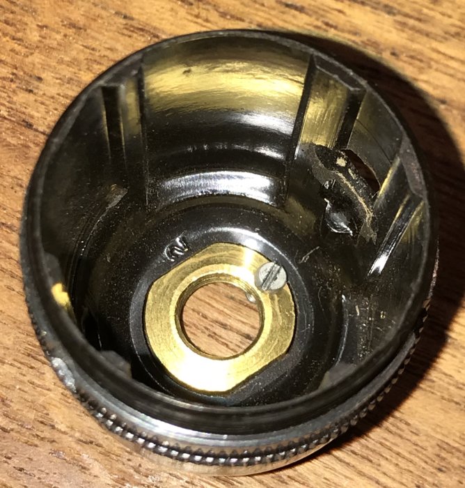 Närbild av en lampsockel med en liten skruv som diskuteras för jordning, visande metalldelar och gängor.