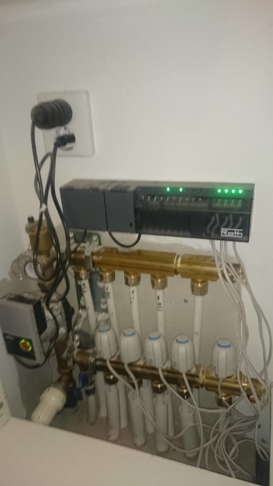 Roth golvvärmesystem med termostatventiler och pump, alla indikatorlampor lyser grönt.