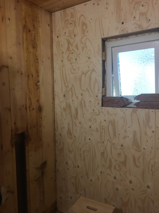 Renoveringsprojekt med nylagt 12mm plywood på väggar runt ett fönster, med utrymme för el och vatten.