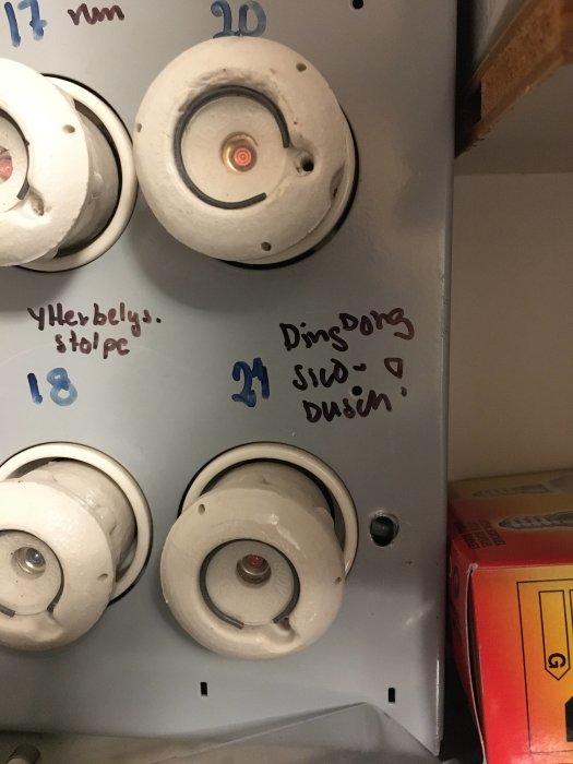 Elskåp med märkning och numrerade säkringsdosor varav en är nummer 21, handskrivna noteringar syns på skåpets insida.