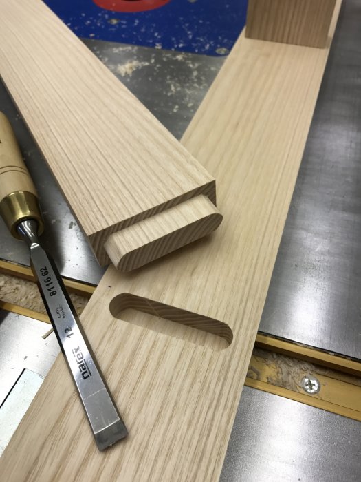Trädetalj för loftsäng i ask, halvfärdigt med utskurna steg och mätkniv för precision.