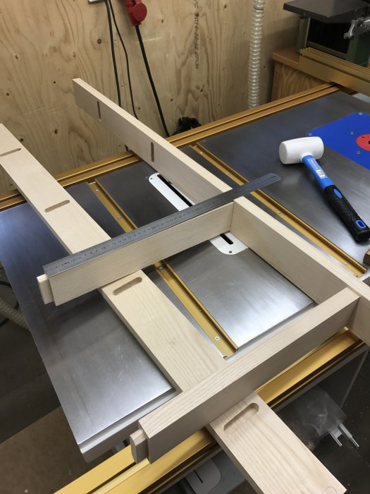 Del av en askträ loftsäng under konstruktion i en verkstad med verktyg synliga.