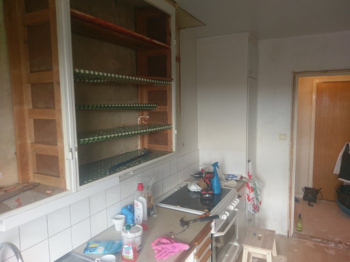 Kök under renovering med borttagna skåpluckor och pågående rivningsarbete.