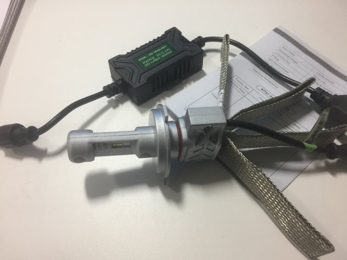 LED-drivrutin och bygglampa på ett bord med installationsschema i bakgrunden.