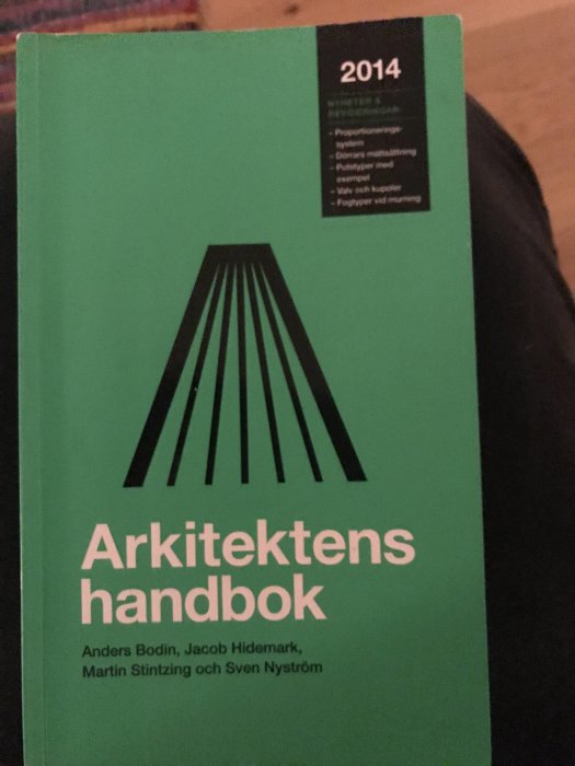 Grön bok med titeln "Arkitektens handbok" och årtal 2014 samt författarnas namn på framsidan.