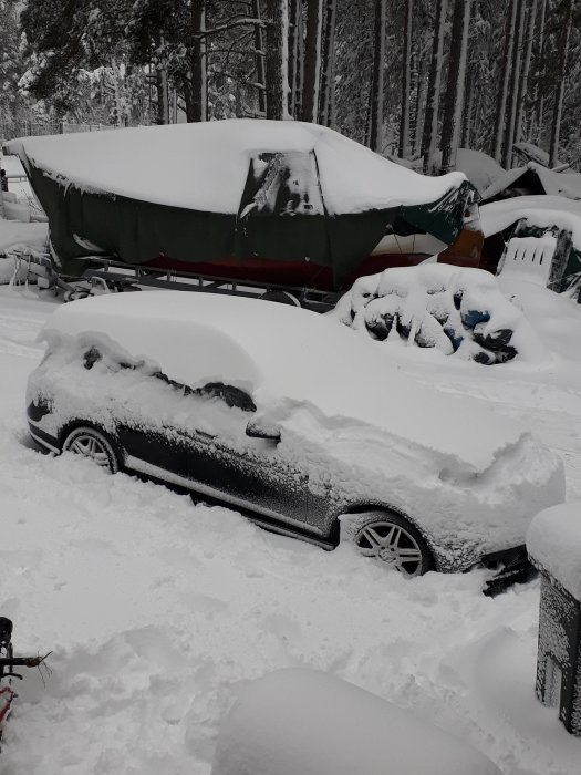 Bil och båt på trailer täckta med tjockt snötäcke omgiven av snötyngd skogsmiljö.