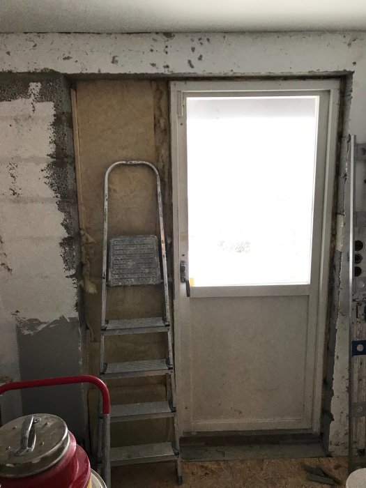 Renoveringsprojekt som visar en delvis igensatt fönsteröppning med leca och nyinstallerad dörr.