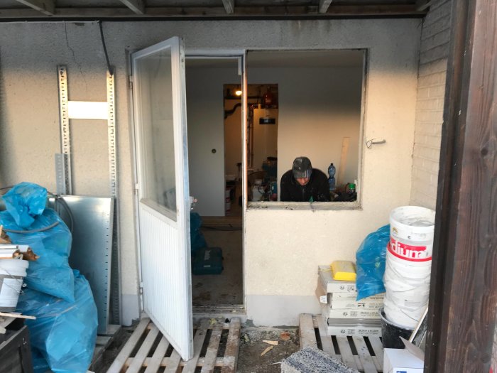 Pågående installation av dörr med sidoljus i en lättbetongvägg med synliga reglar och byggmaterial.