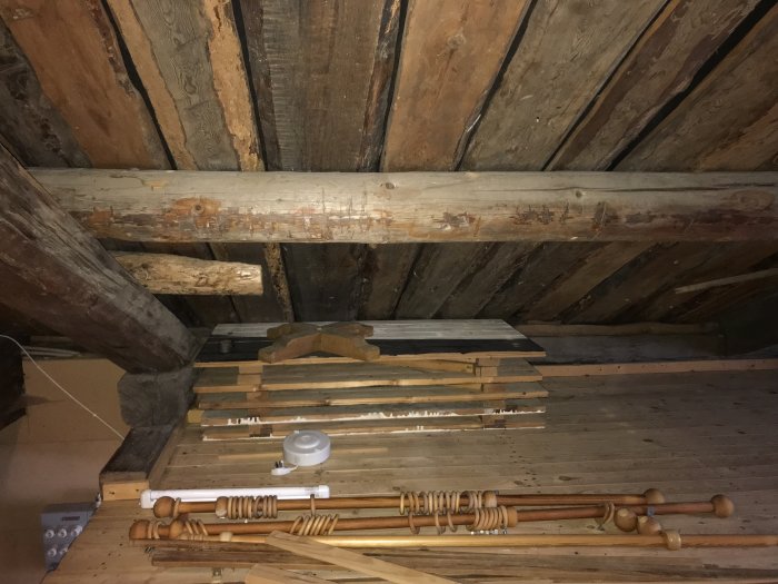 Gammalt hus med träbjälkar och takstolar synliga, planer för renovering med isolering och luftspalt för att förhindra mögel.