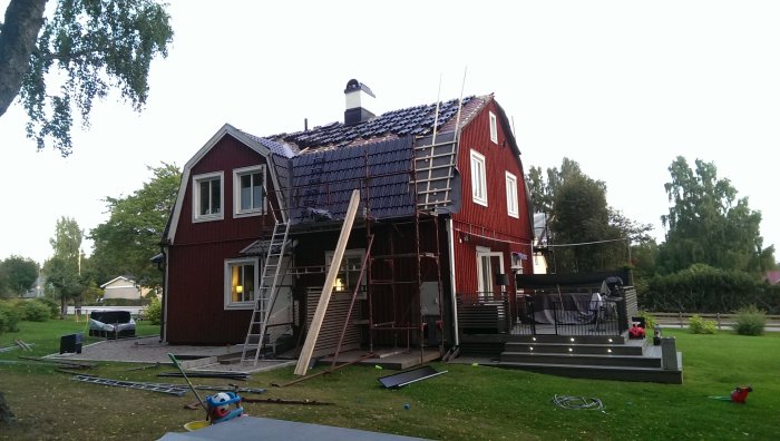 Rött hus under ombyggnad med pågående ommålning och byggställningar.