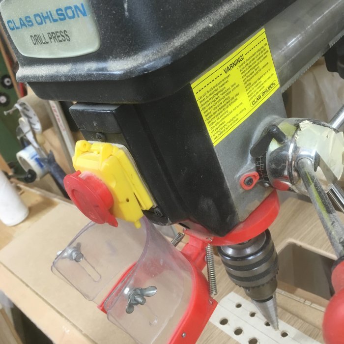 Närbild av pelarborr vid borrning med fokus på varumärket Clas Ohlson och bockad plastskyddsskärm.