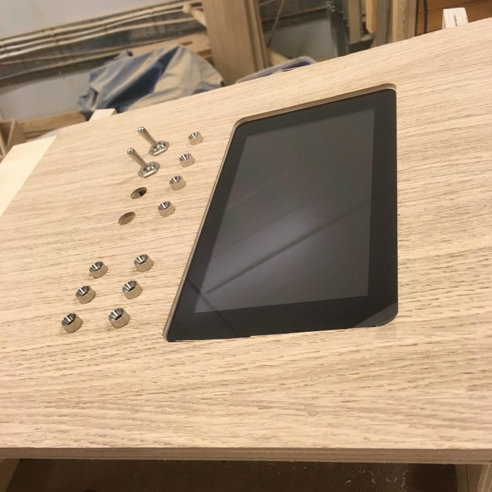 Skärmonterad träpanel med utfrästa hål och vippströmbrytare liggande ovanpå.