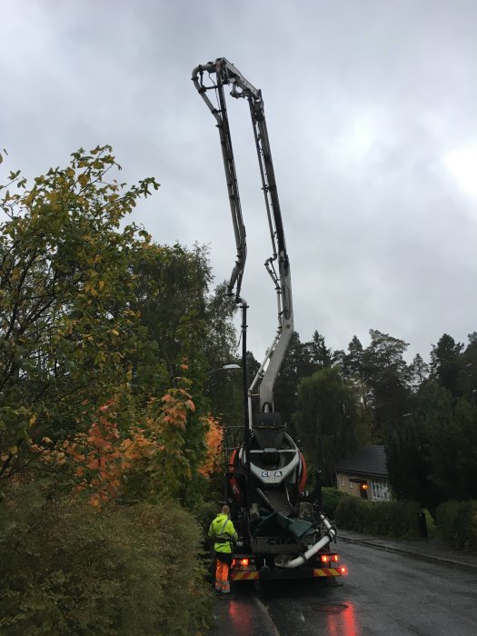 Betongbil med utsträckt pumparm och en arbetare som förbereder gjutningen av en platta.