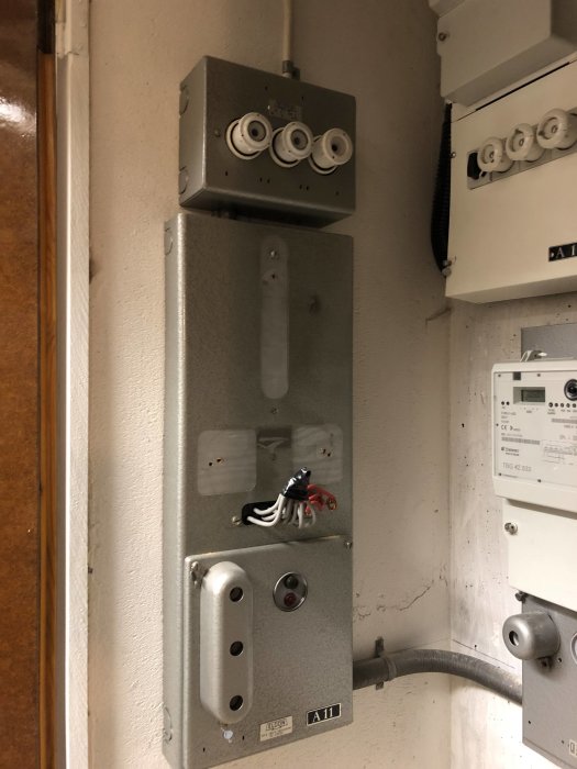 Elskåp med mätare i källare, visar äldre installation med synliga stigar och rör för 3-fas indrag.