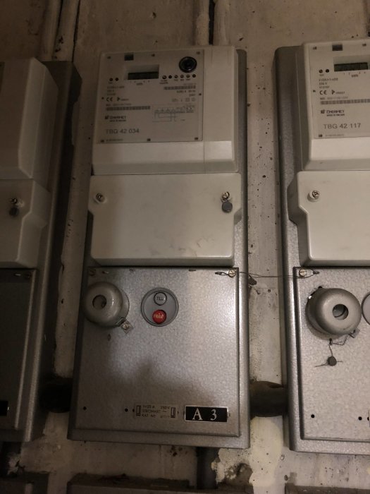 Två elskåp med mätare och 3-fas indragning i en källare, synliga gamla rör och kablar som tyder på äldre installation.