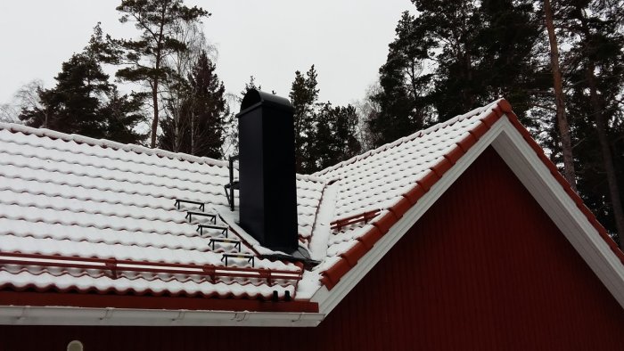 Hus med snötäckt tak och synlig ränndal som leder till hängrännan vid en skorsten.