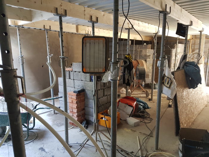 Under-construction interior of a future man cave with wine cellars, showing scaffolding, cement blocks, and construction tools.