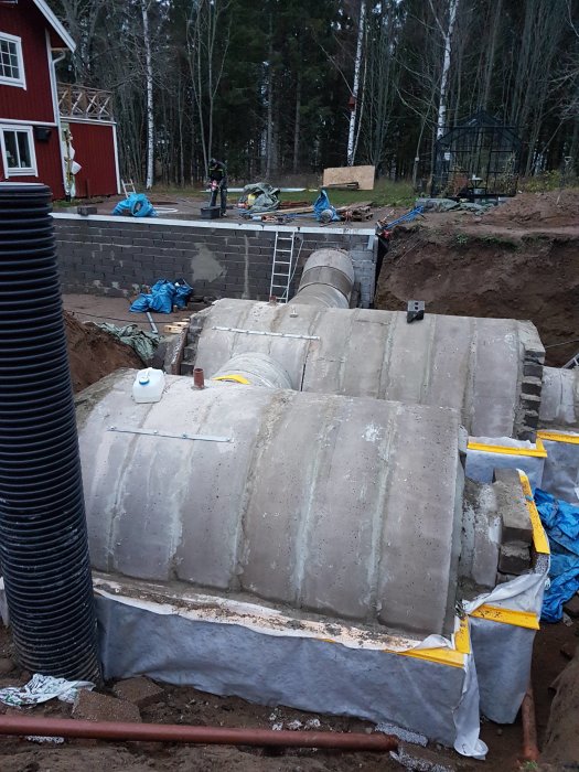 Halverade betongrör används för konstruktionen av en vinkällare med isolering och skyddsduk.