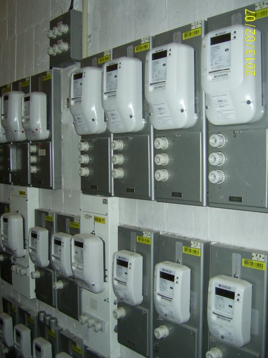 Vägg med flera nya elcentraler och energimätare monterade, märkta med etiketter och installationsdatum.