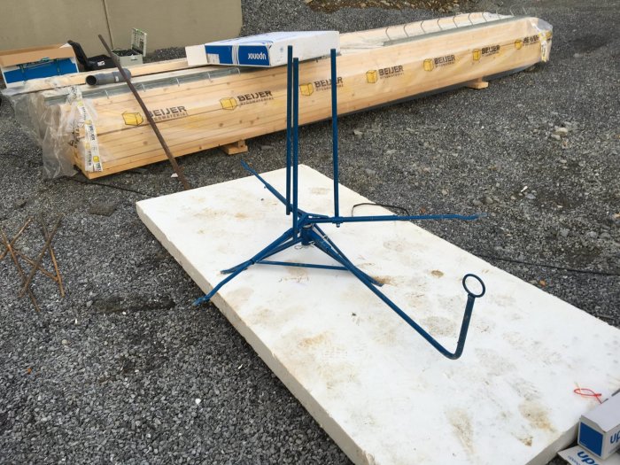En Uponor vindmaskin för golvvärme lägger på en husplatta, med förpackade material i bakgrunden.