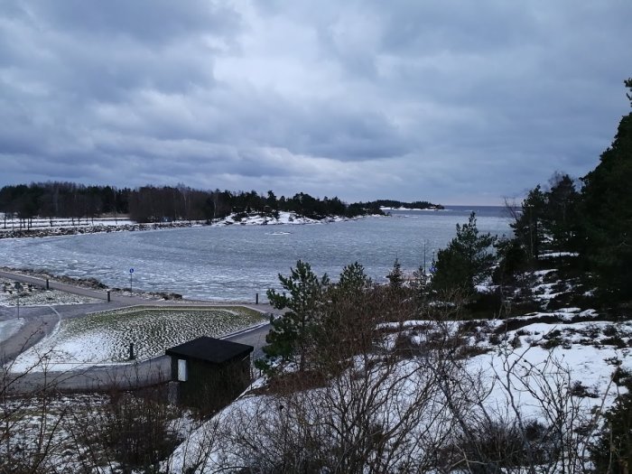 En badvik med drivis vid Vänern under en grå himmel.