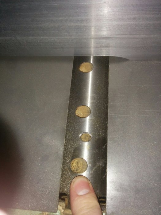 Närbild av en hand som håller i en kniv med en oscillerande cutter delvis skymd av metall.