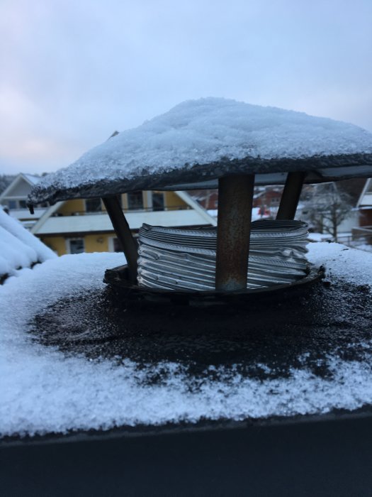 Ventilationsutblås på tak med flexslang och snötäckt skyddshatt.