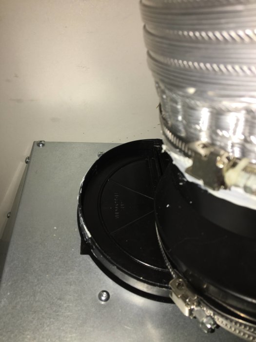 Kallrasskydd i köksfläkt med löst åtdragen slangklämma och ansluten flexibel silverfärgad ventilationskanal.