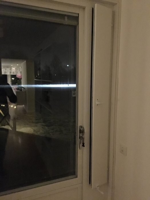 Ventilspringa längs ett fönster i ett mörkt rum, reflektioner syns i glaset.