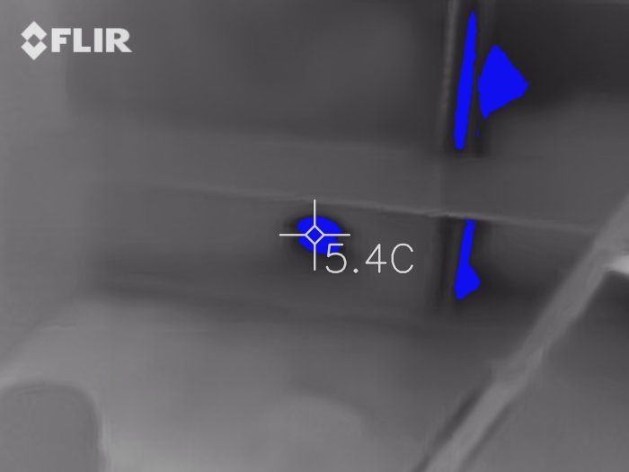 Termisk bild som visar kalluftsläckage i en husklädkammare, markerat med blå färg och 5.4°C.