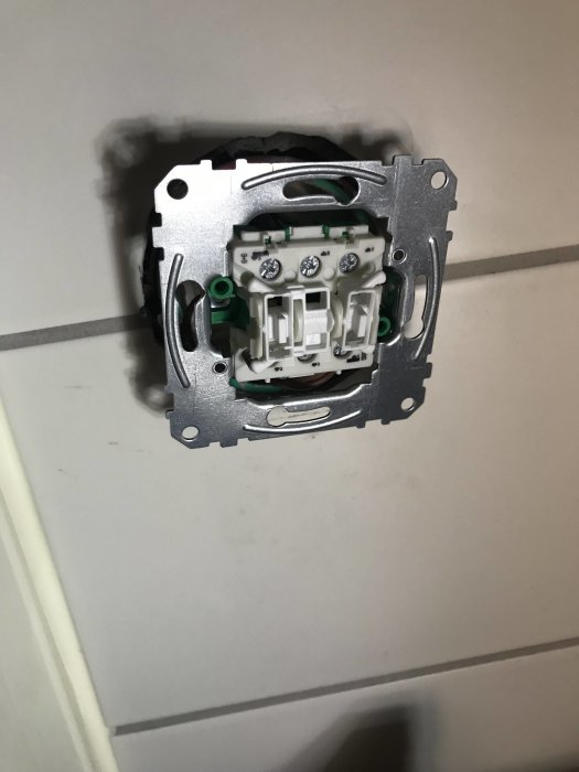 Eluttag utan frontplatta monterat på vägg, kablar synliga, redo för anslutning av dimmer.