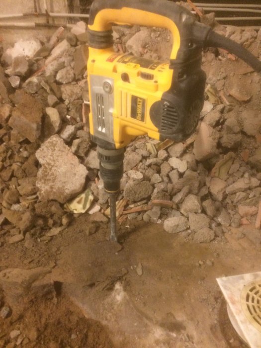 Gul och svart bergborr som används för att bryta upp betonggolv för avloppsarbeten.