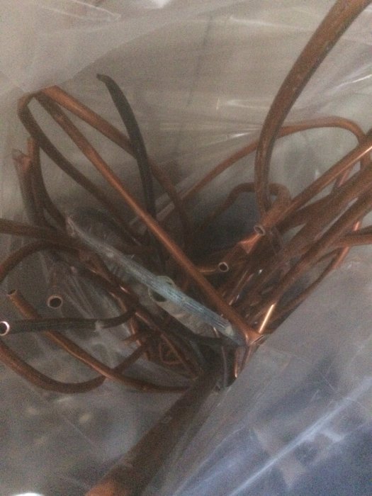 Gamla kopparledningar och rörbitar samlade för återvinning.