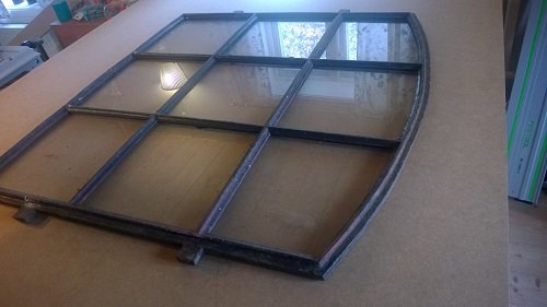 Bågformad karmöverstycke i trä på arbetsbord med grovsågade kanter och synliga märkningar för bearbetning.