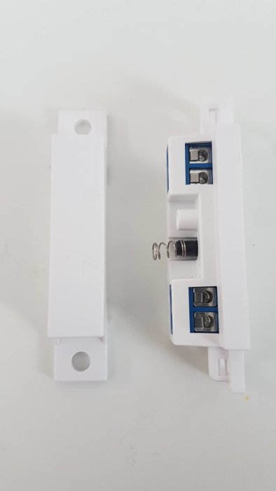 Två elektriska komponenter med pilmarkeringar, en med fjäderbelastad del i mitten.