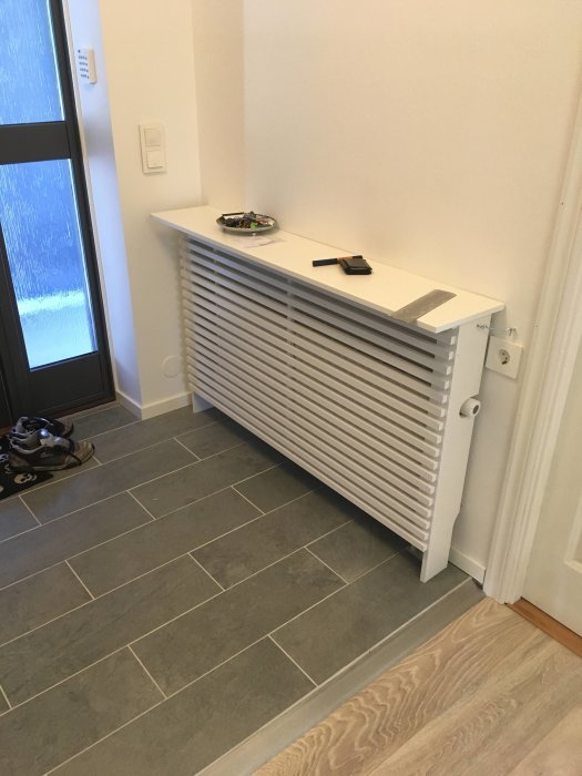 Nyinstallerat elementskydd i en hall, med vägglist och klädhängare, verktyg och skor synliga.