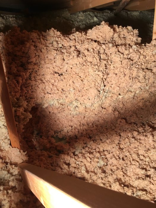 Rosafärgad isolering på vind med synliga träbjälkar, torr med svag missfärgning ovan badrum.