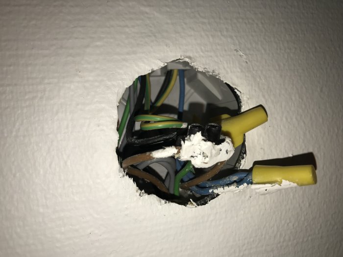 Öppen eldosa med flera elektriska kablar och förgreningar, vissa skyddade med krympslang.