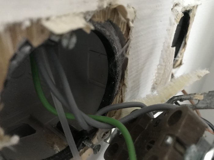 Elinstallation med synliga elledningar som är på väg igenom ett rör mellan två dosor i en öppen väggkonstruktion.