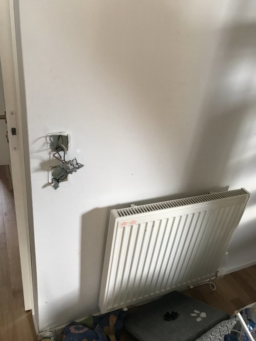 Vägg med ett öppet och gammalt telejack ovanför ett fast installerat element.
