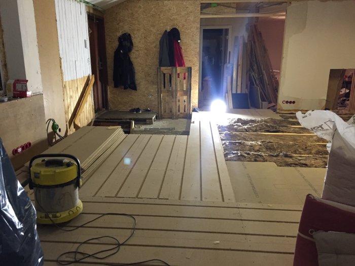 Renovering av vardagsrumsgolv med delvis lagda golvbrädor och isoleringsmaterial synligt.