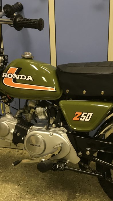 Nyrenoverad grön Honda-motorcykel med nylackerad tank och sidokåpa, blank finish och dekaler.