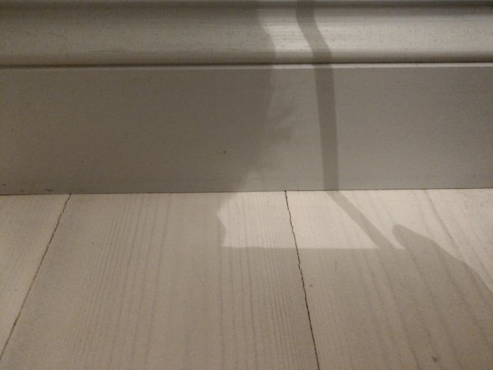Noggrant hyvlad sockel utan springa mot ett trägolv, vilket visar hantverksskicklighet i detaljerna.
