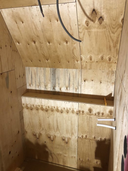 Reglat och med plywood klädd vägg med inbyggd hylla under konstruktion i ett byggprojekt.