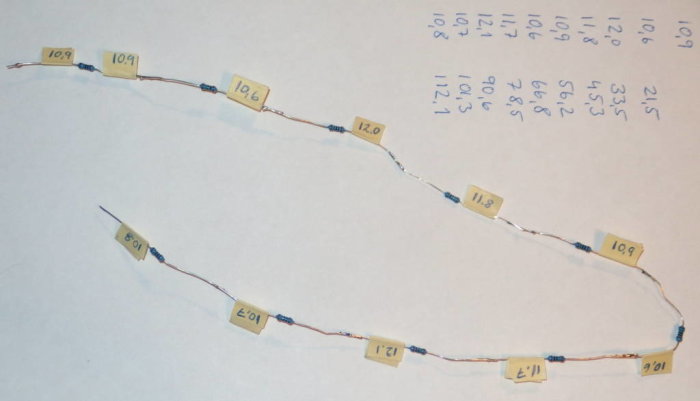 Motståndsstege lödd med individuellt mätta och märkta motstånd ligger på ett papper.