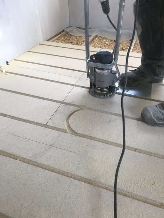 Användning av en handöverfräs för att skapa vändningar i färdigspårade skivor på en byggarbetsplats.