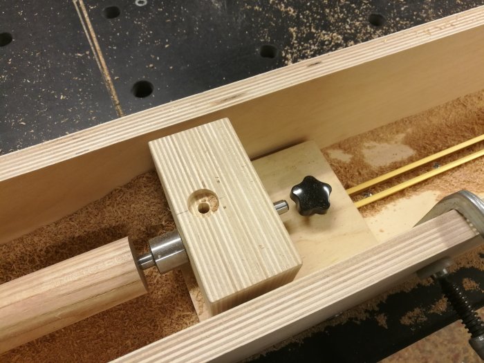 Detaljbild av en hemmagjord träbearbetningsapparat med rundstav i ek, kullager, och justerbar spännanordning.